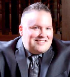 A man in suit and tie smiling for the camera.