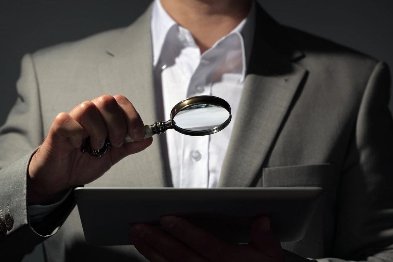 A man holding a tablet and magnifying glass.