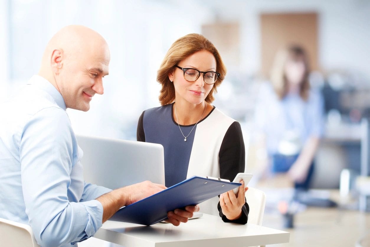 A man and woman looking at papers on a table.